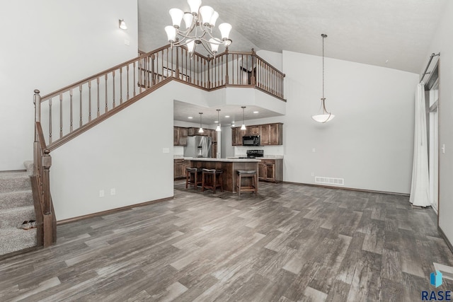 204 E 81st Pl, Sioux Falls, SD 57108 - unfurnished living room featuring visible vents, a notable chandelier, dark wood-style floors, a towering ceiling, and stairs