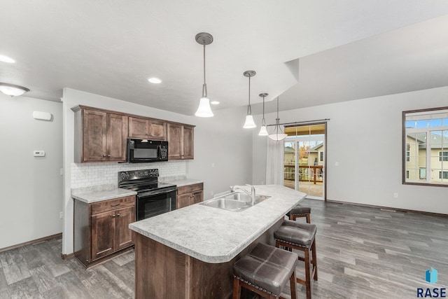 204 E 81st Pl, Sioux Falls, SD 57108 - kitchen featuring black appliances, a sink, a breakfast bar area, light countertops, and decorative backsplash