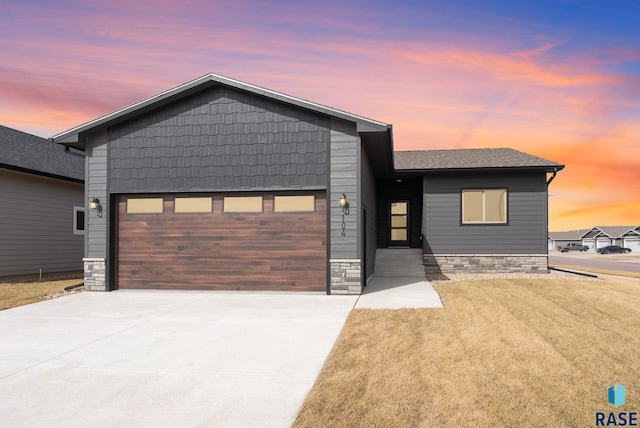 view of front of home featuring driveway, a front lawn, roof with shingles, and an attached garage