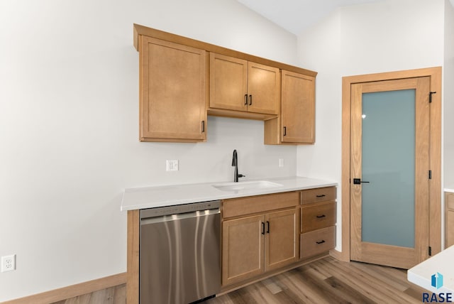 kitchen with stainless steel dishwasher, light countertops, light wood-style floors, and a sink