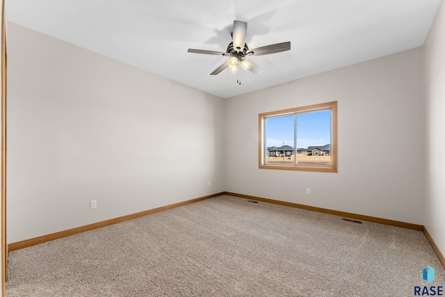 carpeted spare room featuring visible vents, a ceiling fan, and baseboards