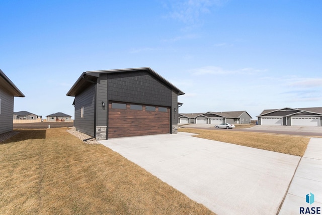 exterior space featuring stone siding, a lawn, concrete driveway, and an outdoor structure