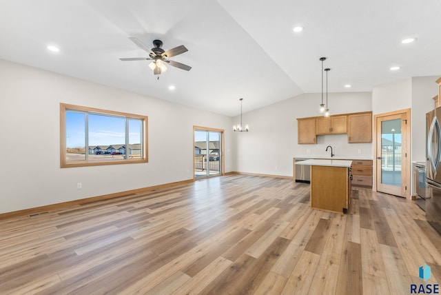 kitchen featuring a kitchen island, open floor plan, light countertops, light wood-style floors, and a sink