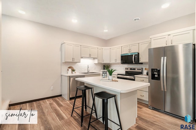 5714 E Avett Pl, Sioux Falls, SD 57108 - kitchen with light countertops, a kitchen bar, decorative backsplash, appliances with stainless steel finishes, and a sink