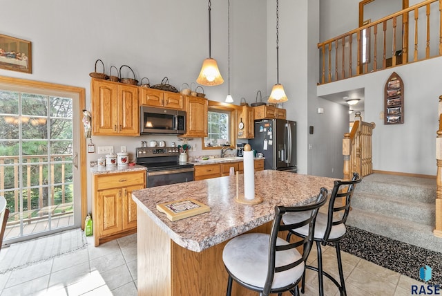 6305 Lakeview Dr, Wentworth, SD 57075 - kitchen featuring a breakfast bar area, a towering ceiling, light tile patterned flooring, stainless steel appliances, and a sink