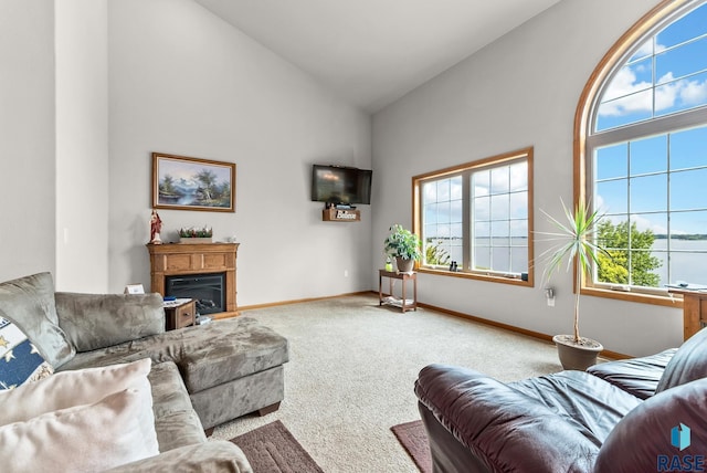 6305 Lakeview Dr, Wentworth, SD 57075 - living area with carpet flooring, high vaulted ceiling, baseboards, and a glass covered fireplace