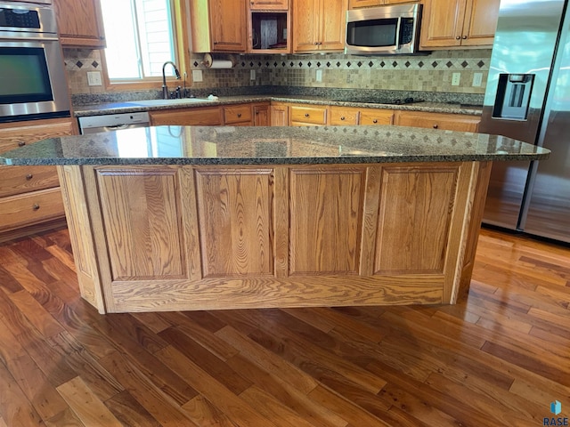 800 W Sterling Oak Cir, Sioux Falls, SD 57108 - kitchen with stainless steel appliances, dark wood finished floors, decorative backsplash, a kitchen island, and dark stone countertops