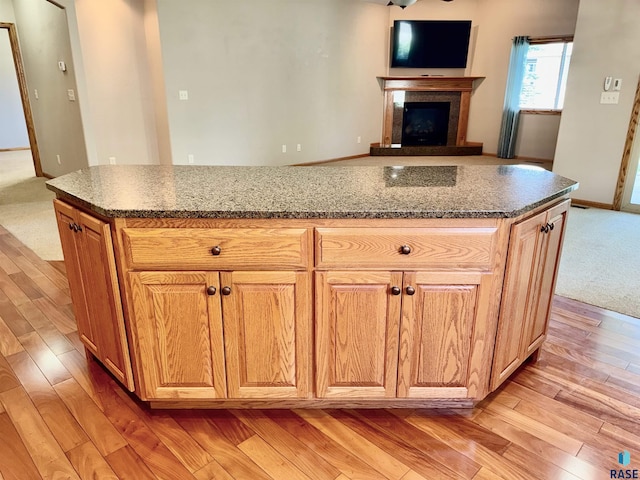 800 W Sterling Oak Cir, Sioux Falls, SD 57108 - kitchen with a fireplace with raised hearth, light wood-style flooring, a center island, dark stone counters, and open floor plan