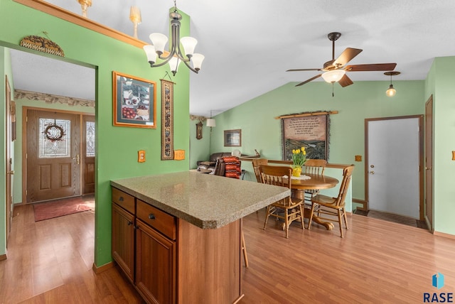 kitchen with pendant lighting, ceiling fan with notable chandelier, light wood-type flooring, and brown cabinets