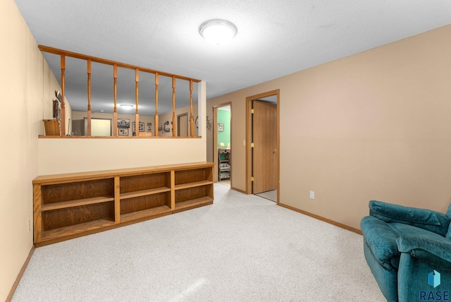 living area with baseboards, a textured ceiling, and carpet flooring