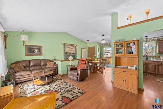 living room with wood finished floors, a ceiling fan, and vaulted ceiling