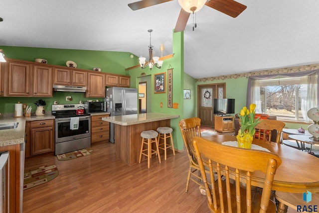 kitchen with vaulted ceiling, light countertops, under cabinet range hood, and stainless steel appliances