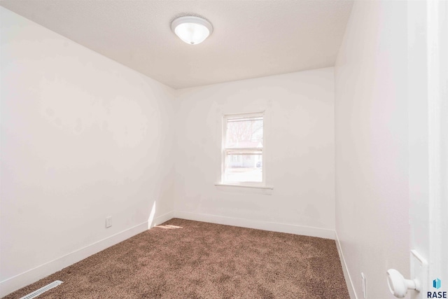 spare room featuring visible vents, carpet flooring, and baseboards