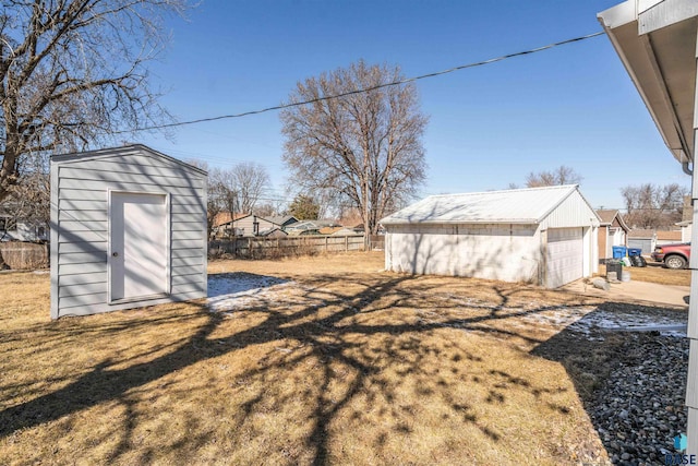 view of yard with a detached garage, an outbuilding, a storage shed, and fence
