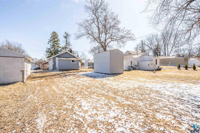 view of yard featuring a storage shed, an outbuilding, fence, and a residential view