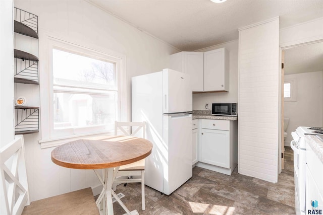 kitchen featuring white appliances, white cabinetry, and light countertops