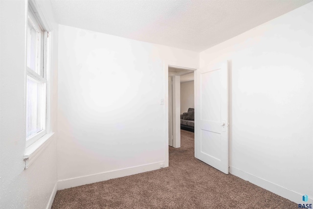 carpeted empty room featuring baseboards and a textured ceiling