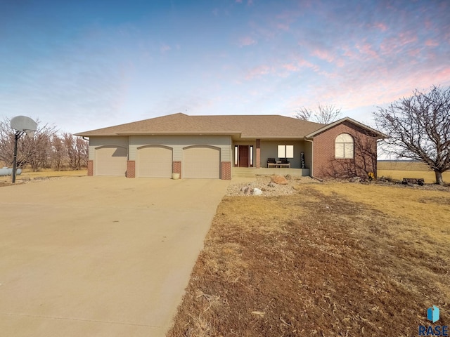 27702 481st Ave, Canton, SD 57013 - ranch-style house with brick siding, an attached garage, concrete driveway, covered porch, and a shingled roof