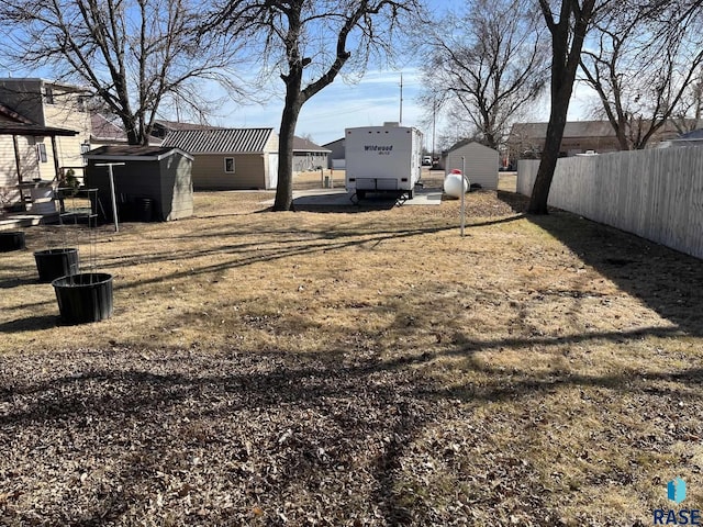 view of yard with an outbuilding, a storage shed, and fence