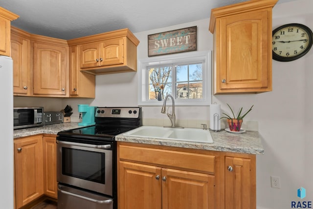 kitchen featuring appliances with stainless steel finishes, a textured ceiling, light countertops, and a sink
