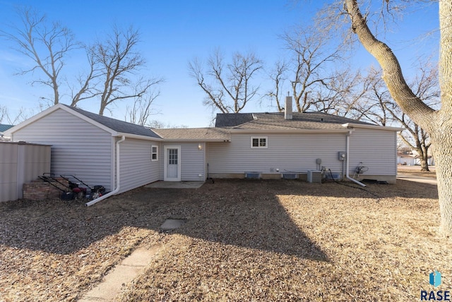 back of property with cooling unit, a chimney, and a shingled roof