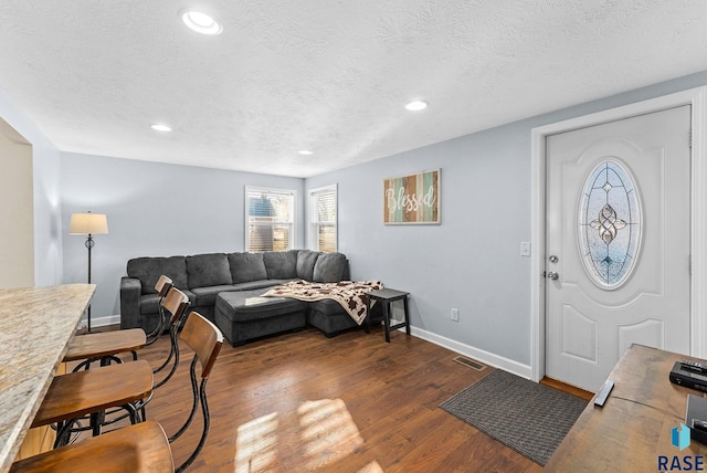 living area with visible vents, baseboards, recessed lighting, dark wood-type flooring, and a textured ceiling