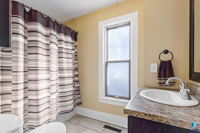 bathroom featuring vanity, toilet, a textured ceiling, tile patterned floors, and visible vents