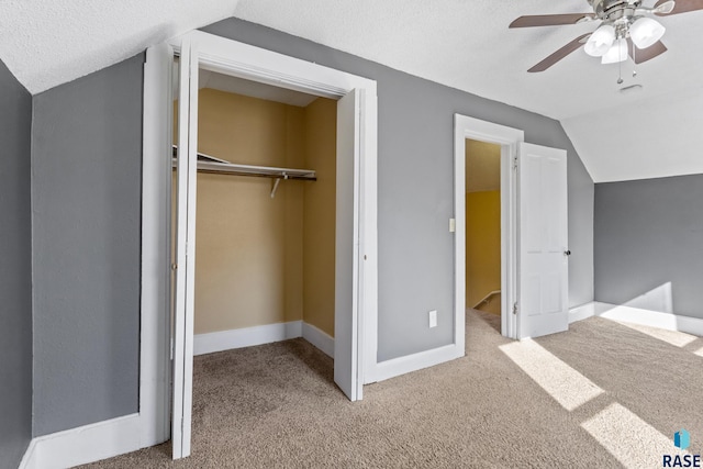 unfurnished bedroom with vaulted ceiling, a closet, carpet flooring, and a textured ceiling