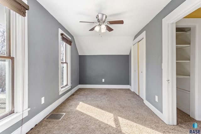unfurnished bedroom featuring baseboards, visible vents, vaulted ceiling, and carpet