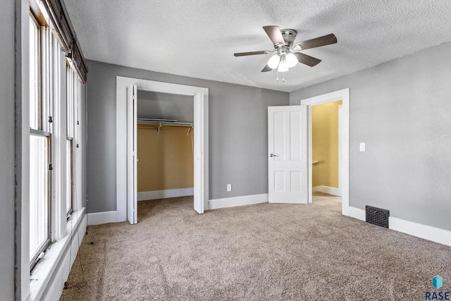 unfurnished bedroom with carpet flooring, baseboards, a textured ceiling, visible vents, and a closet