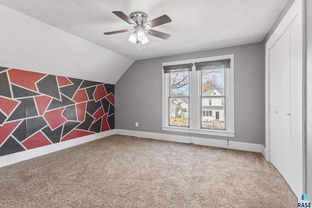 additional living space with carpet flooring, a textured ceiling, vaulted ceiling, and ceiling fan