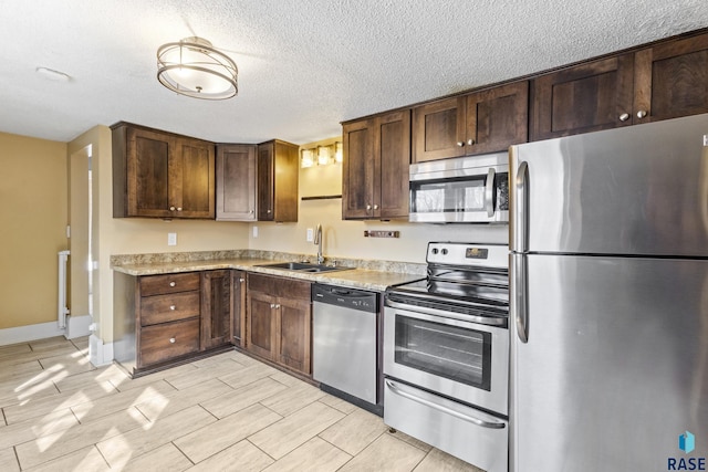 kitchen featuring light countertops, stainless steel appliances, wood finish floors, dark brown cabinetry, and a sink