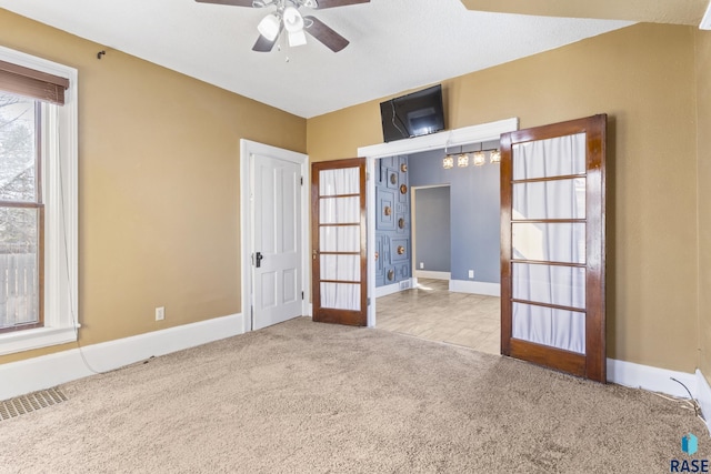 carpeted empty room with baseboards, visible vents, and a ceiling fan