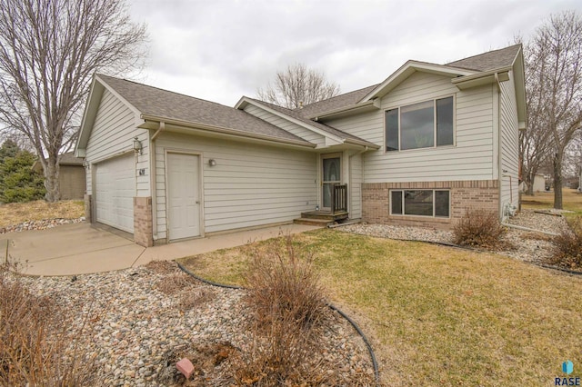 tri-level home featuring brick siding, a garage, a front yard, and roof with shingles