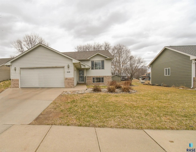 tri-level home featuring an attached garage, brick siding, a front lawn, roof with shingles, and driveway