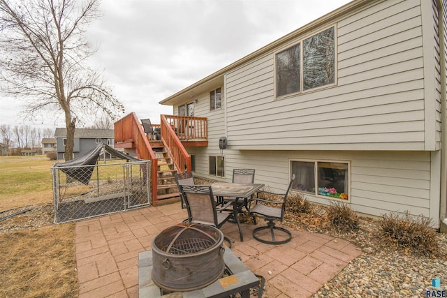 view of patio / terrace with outdoor dining space, a wooden deck, stairs, and a fire pit
