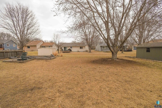 view of yard with a storage unit, fence, an outdoor structure, and a residential view