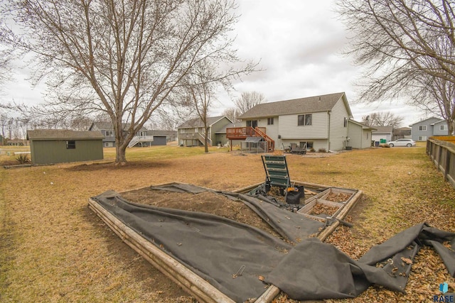 view of yard featuring fence, a wooden deck, stairway, an outbuilding, and a shed