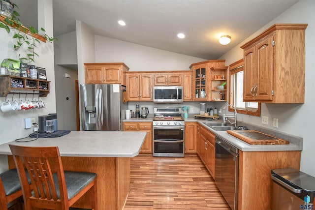 kitchen with appliances with stainless steel finishes, a sink, open shelves, light wood-type flooring, and vaulted ceiling