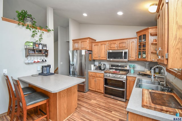 kitchen with light countertops, stainless steel appliances, glass insert cabinets, light wood-type flooring, and vaulted ceiling