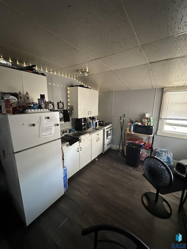 kitchen featuring a sink, white cabinetry, dark wood-style flooring, white appliances, and a drop ceiling