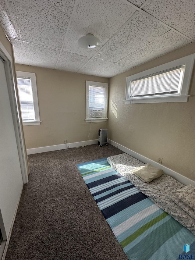 unfurnished bedroom with baseboards, carpet flooring, a paneled ceiling, and multiple windows