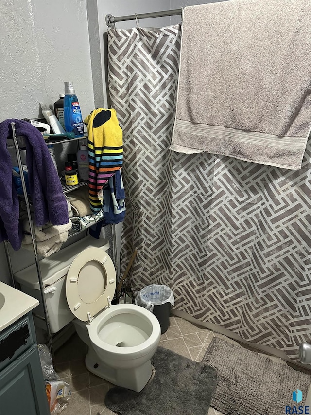 bathroom with tile patterned floors, toilet, vanity, and a textured wall