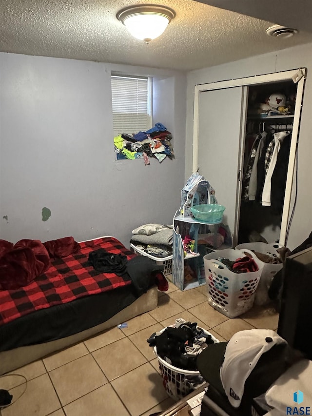 tiled bedroom featuring a closet and a textured ceiling
