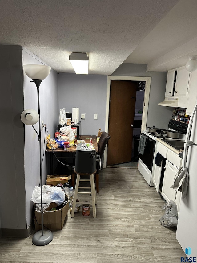 kitchen featuring white electric stove, white cabinetry, light wood-style flooring, and a textured ceiling