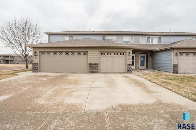 multi unit property featuring brick siding, a garage, and concrete driveway