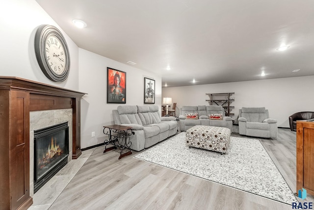 living room with light wood-style flooring, a tile fireplace, baseboards, and recessed lighting