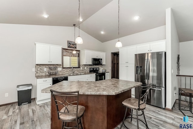 kitchen featuring a kitchen breakfast bar, a sink, backsplash, and black appliances