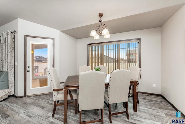 dining area with baseboards, a chandelier, and light wood-style floors