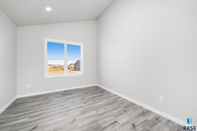 empty room with baseboards, lofted ceiling, wood finished floors, and recessed lighting